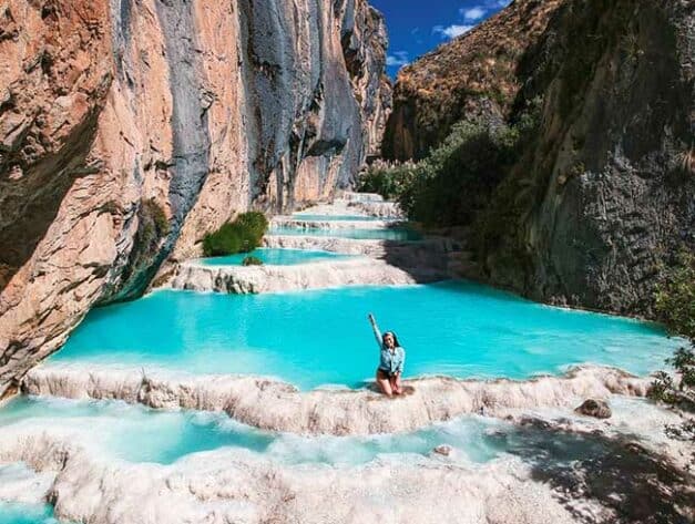 tourist posing for a photo in the turquoise waters of Ayacucho | Ile Tours