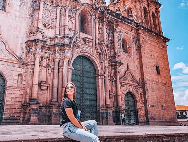 Tourist posing in front of the cathedral in the Main Square of Cusco | Ile Tours