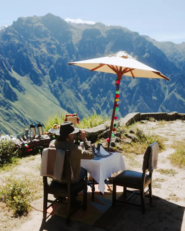 American tourists enjoying a luxurious meal at an elegant table with Machu Picchu in the background | Ile Tours