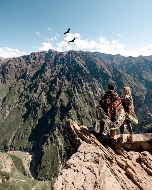 Romantic couple standing on a ledge with a breathtaking view of the mountains in Peru | Ile Tours