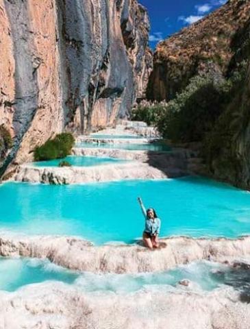 tourist posing for a photo in the turquoise waters of Ayacucho | Ile Tours